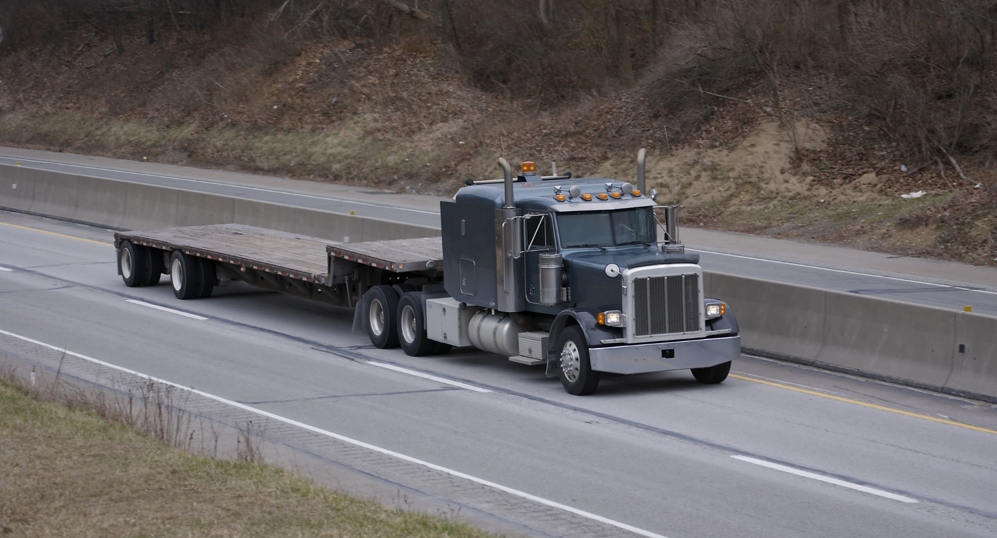 truck with flatbed trailer driving down a highway